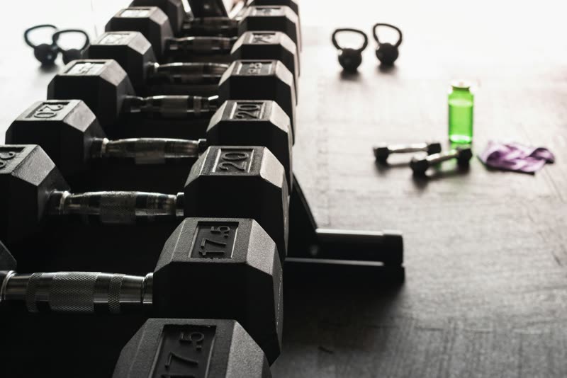 Fileira de halteres e kettlebells no chão da academia