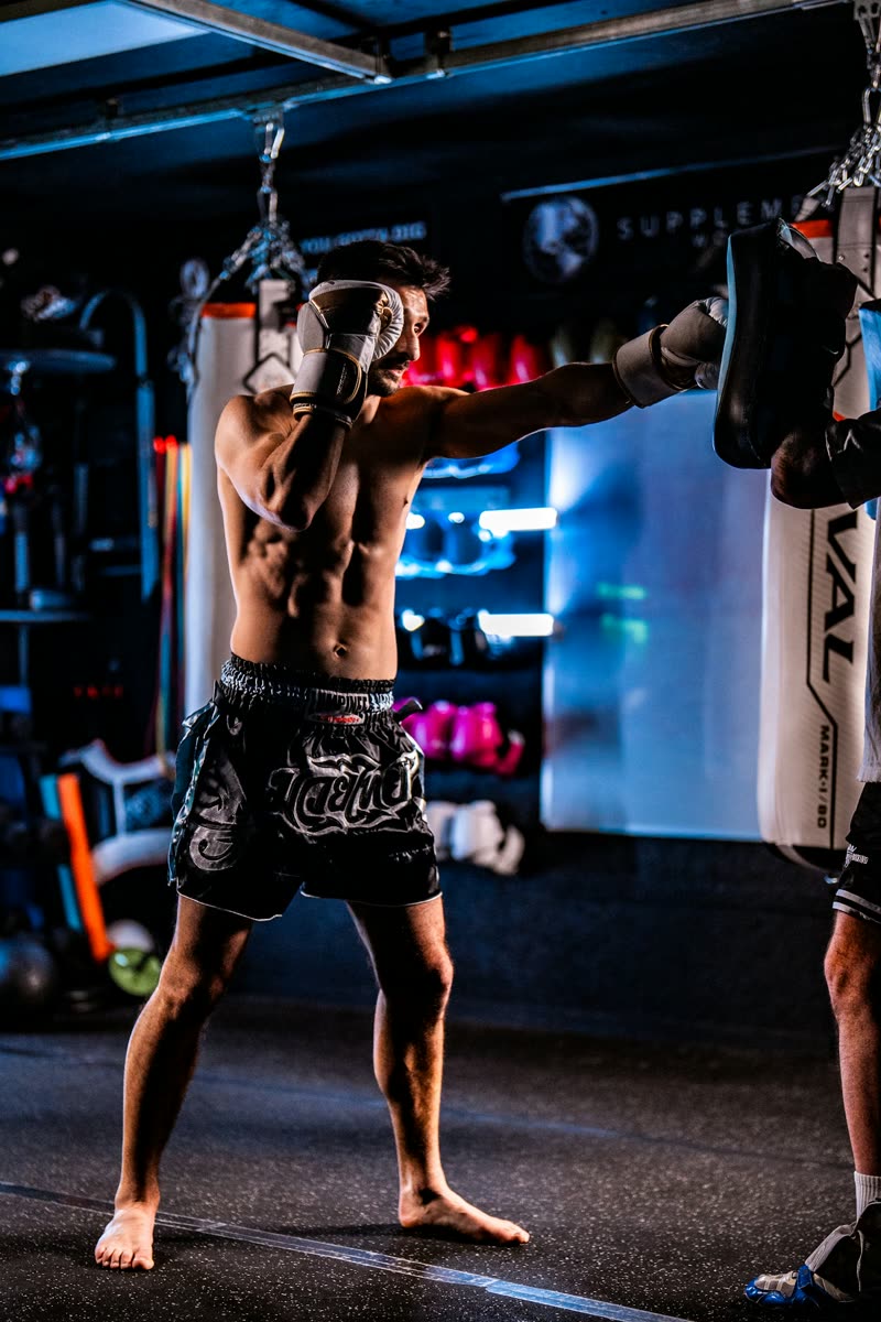 Aluno treinando chutes e socos de muay thai com o professor